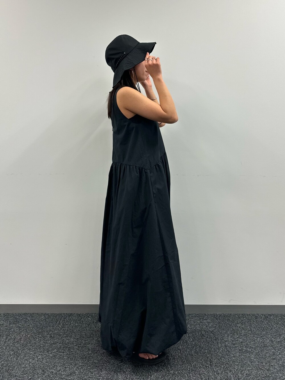 ブラック系のワンピース、ブラック系のハットを着用したレディースの春コーディネートの2枚目の写真