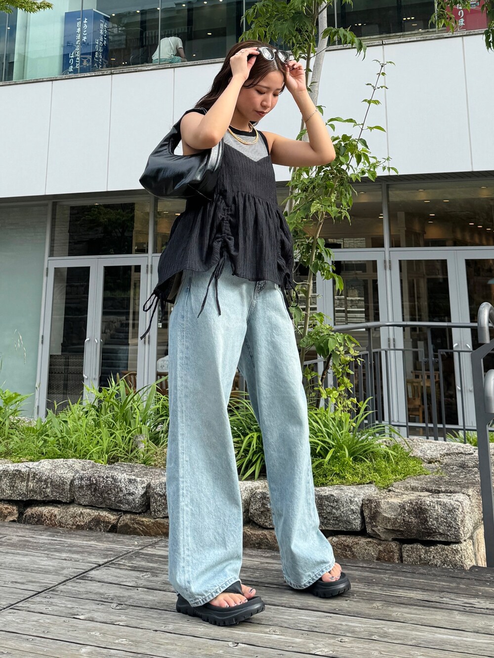 グレー系のタンクトップ、ブラック系のシャツ/ブラウス、ブルー系のデニムパンツを着用したレディースの夏コーディネートの4枚目の写真