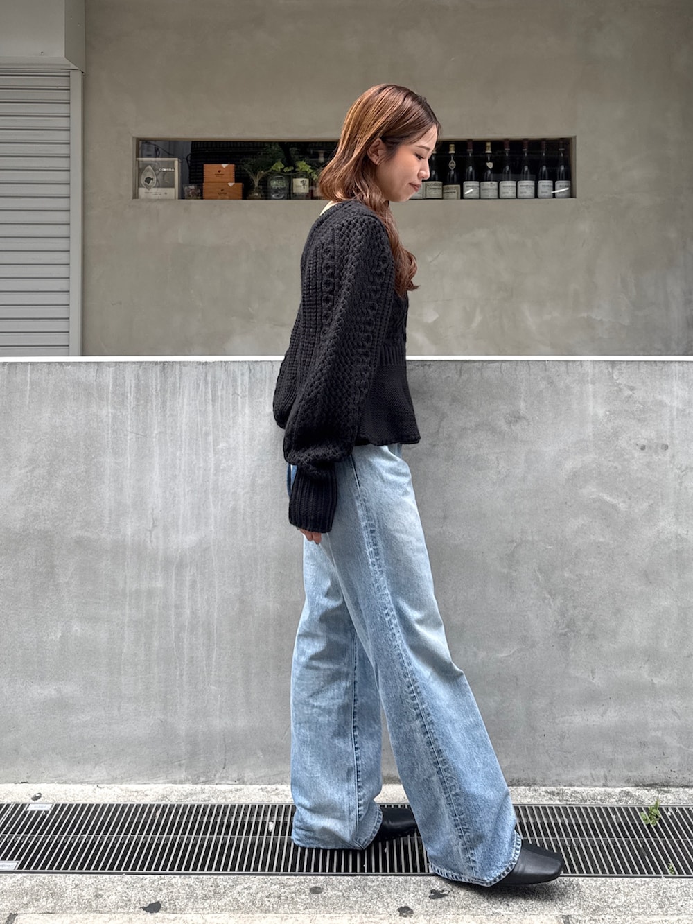 ブラック系のニット/セーター、ブルー系のデニムパンツ、ブラック系のサンダルを着用したレディースの秋コーディネートの2枚目の写真
