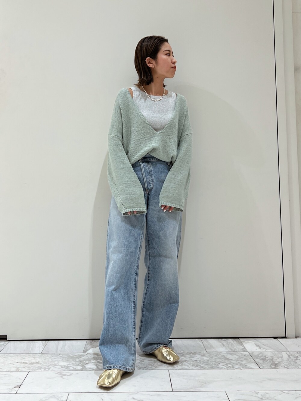 ブルー系のデニムパンツ、イエロー系のパンプス、グリーン系のニット/セーターを着用したレディースの冬コーディネートの6枚目の写真