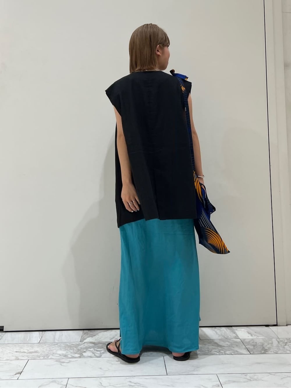 ブラック系のベスト、ブラック系のサンダル、ブルー系のスカートを着用したレディースの夏コーディネートの3枚目の写真