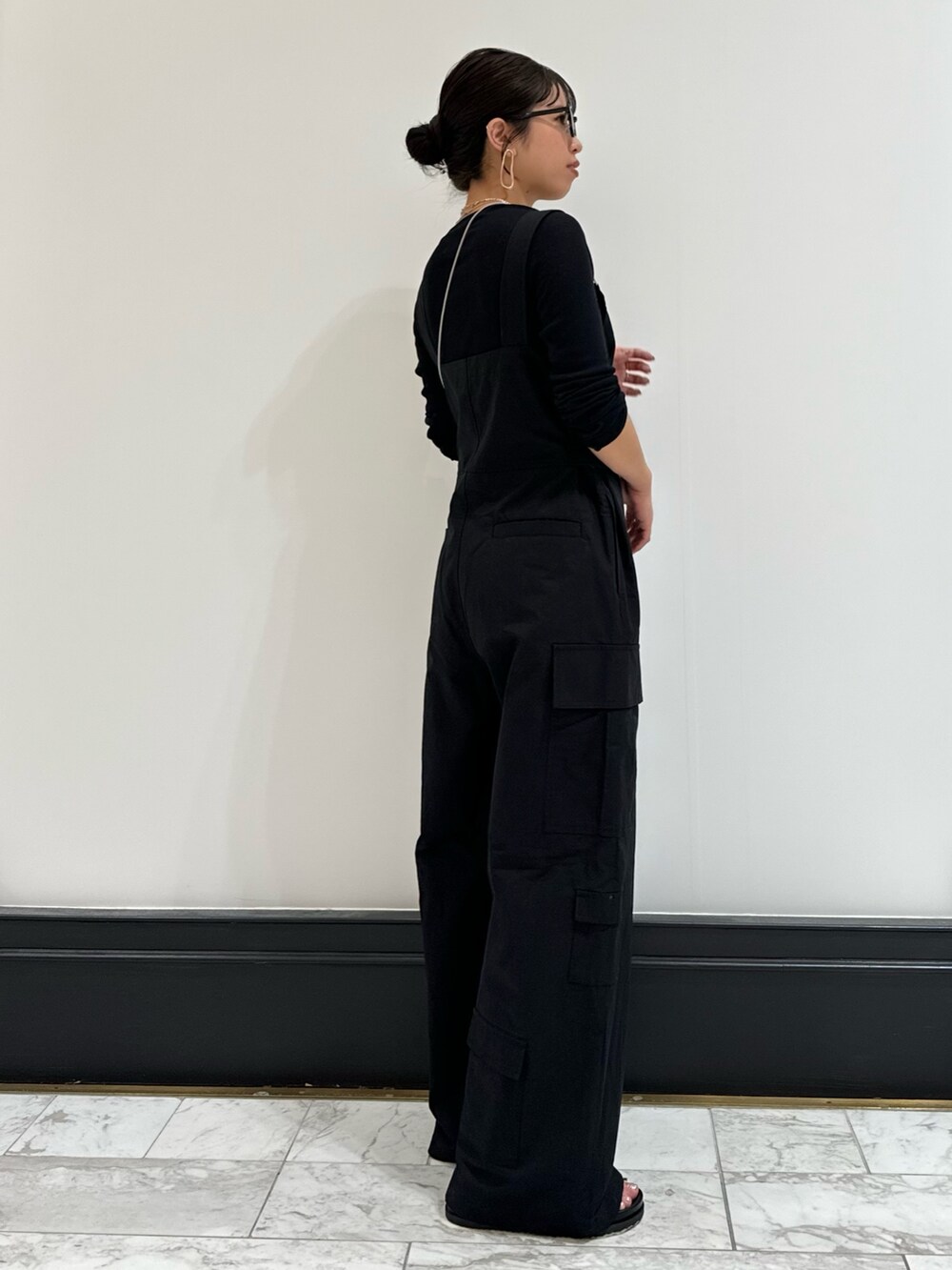 ブラック系のつなぎ/オールインワン、ブラック系のTシャツ/カットソー、ブラック系のサンダルを着用したレディースの冬コーディネートの3枚目の写真