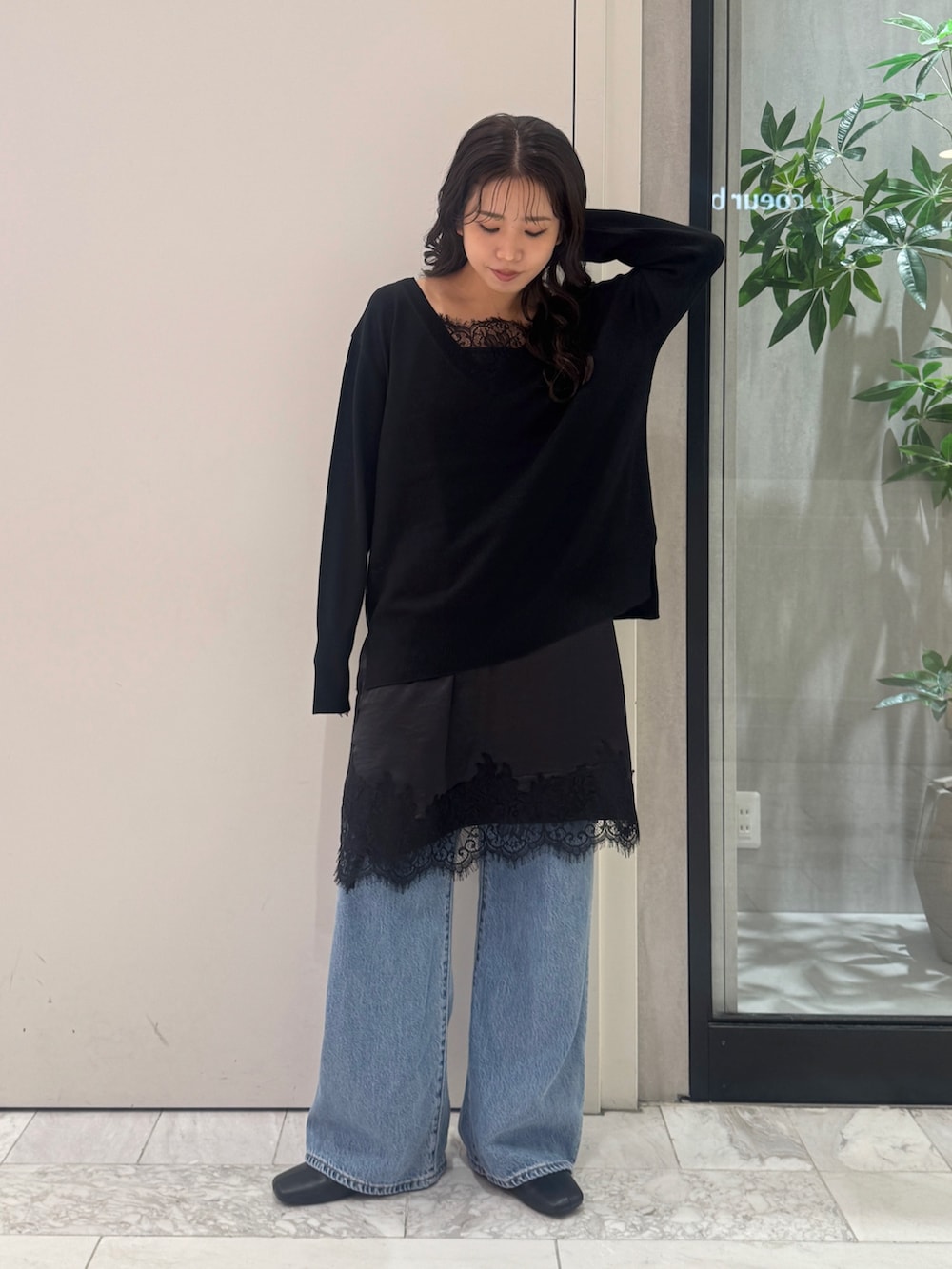 ブラック系のニット/セーター、ブラック系のワンピース、ブルー系のデニムパンツを着用したレディースの秋コーディネートの4枚目の写真