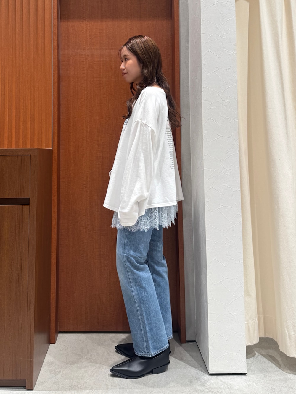 グレー系のキャミソール、ホワイト系のスウェット、ブルー系のデニムパンツを着用したレディースの秋コーディネートの4枚目の写真