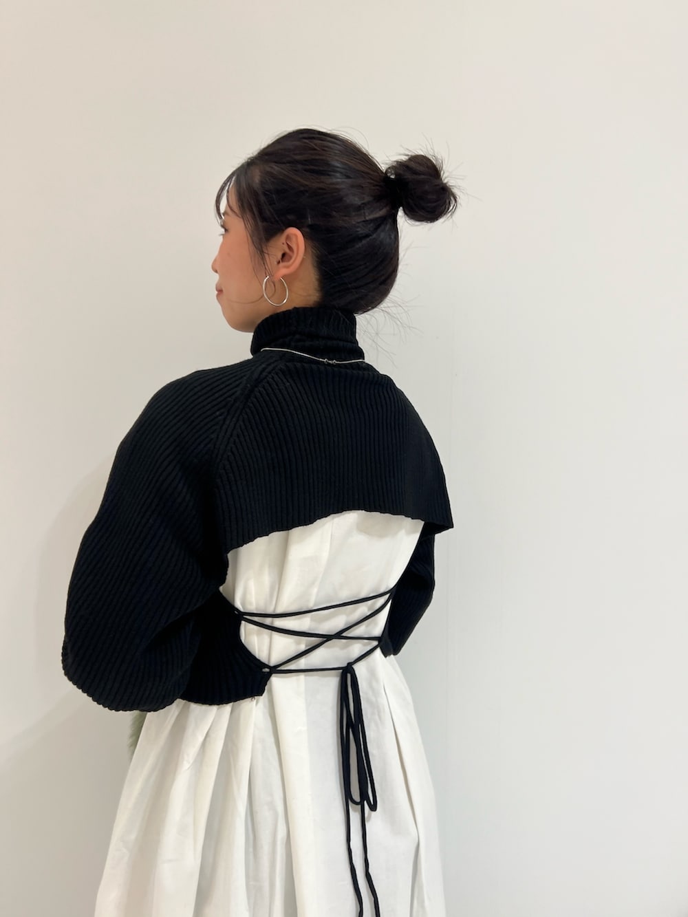 ブラック系のワンピース、グリーン系のハンドバッグ、ブラウン系のブーツを着用したレディースの冬コーディネートの5枚目の写真