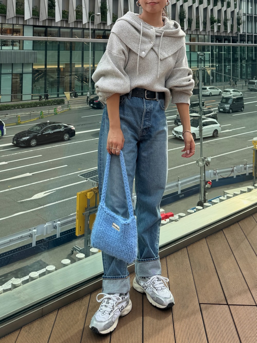 ブルー系のハンドバッグ、グレー系のニット/セーター、ブルー系のデニムパンツを着用したレディースの秋コーディネートの2枚目の写真