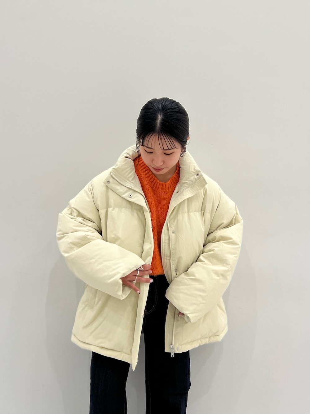 オレンジ系のニット/セーター、ブルー系のデニムパンツ、ホワイト系のダウンジャケット/コートを着用したレディースの秋コーディネートの5枚目の写真