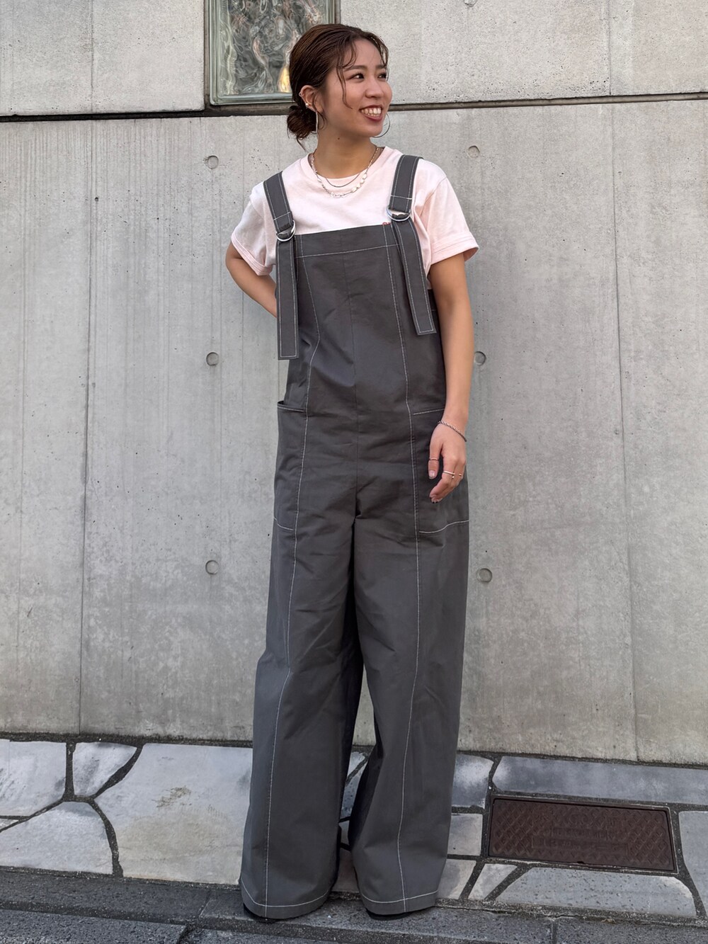 ピンク系のTシャツ/カットソー、ブラック系のサロペット/オーバーオール、ブラック系のサンダルを着用したレディースの春コーディネートの6枚目の写真