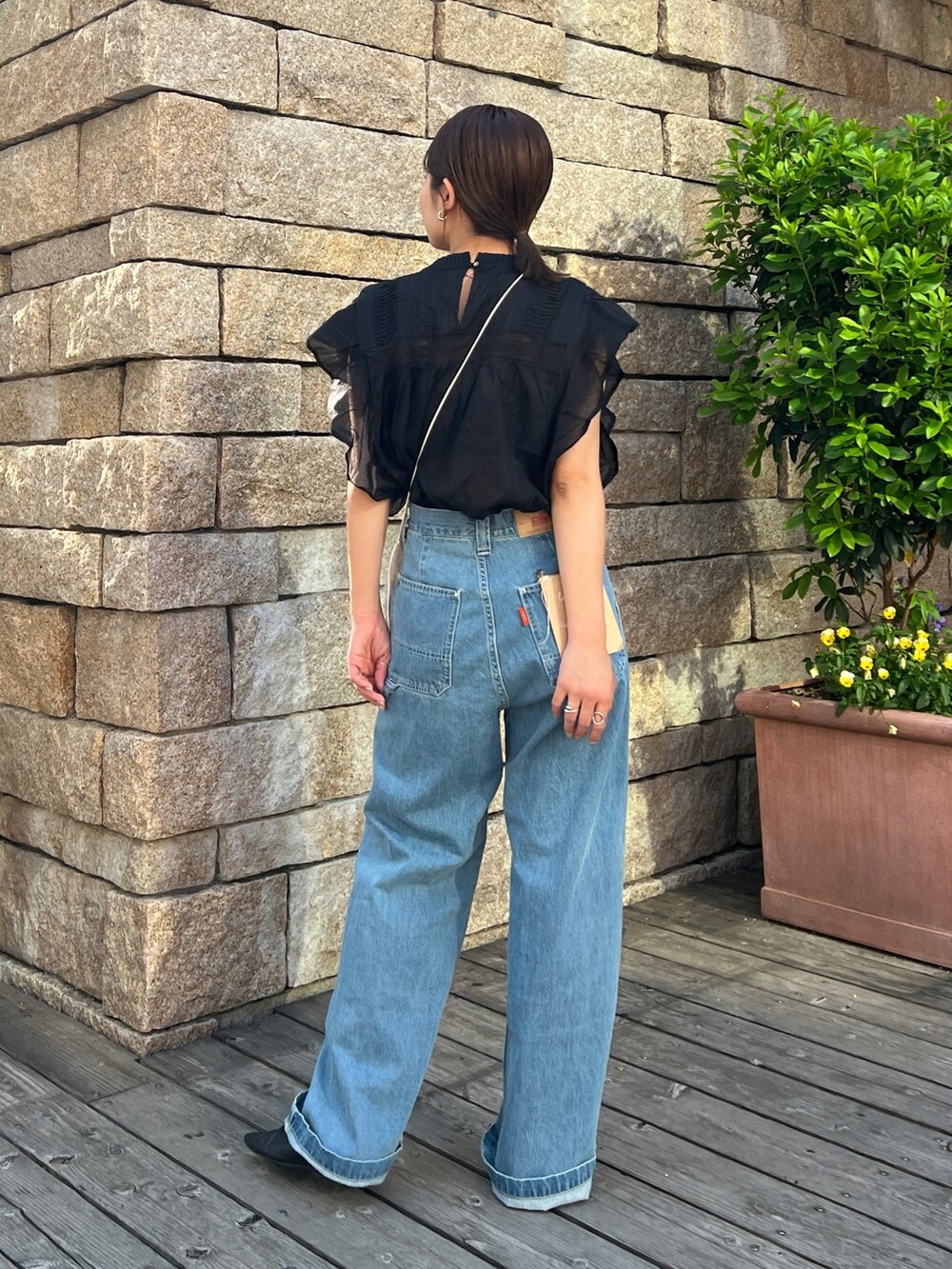 ブルー系のデニムパンツ、ブラック系のパンプス、ブラック系のシャツ/ブラウスを着用したレディースの春コーディネートの3枚目の写真