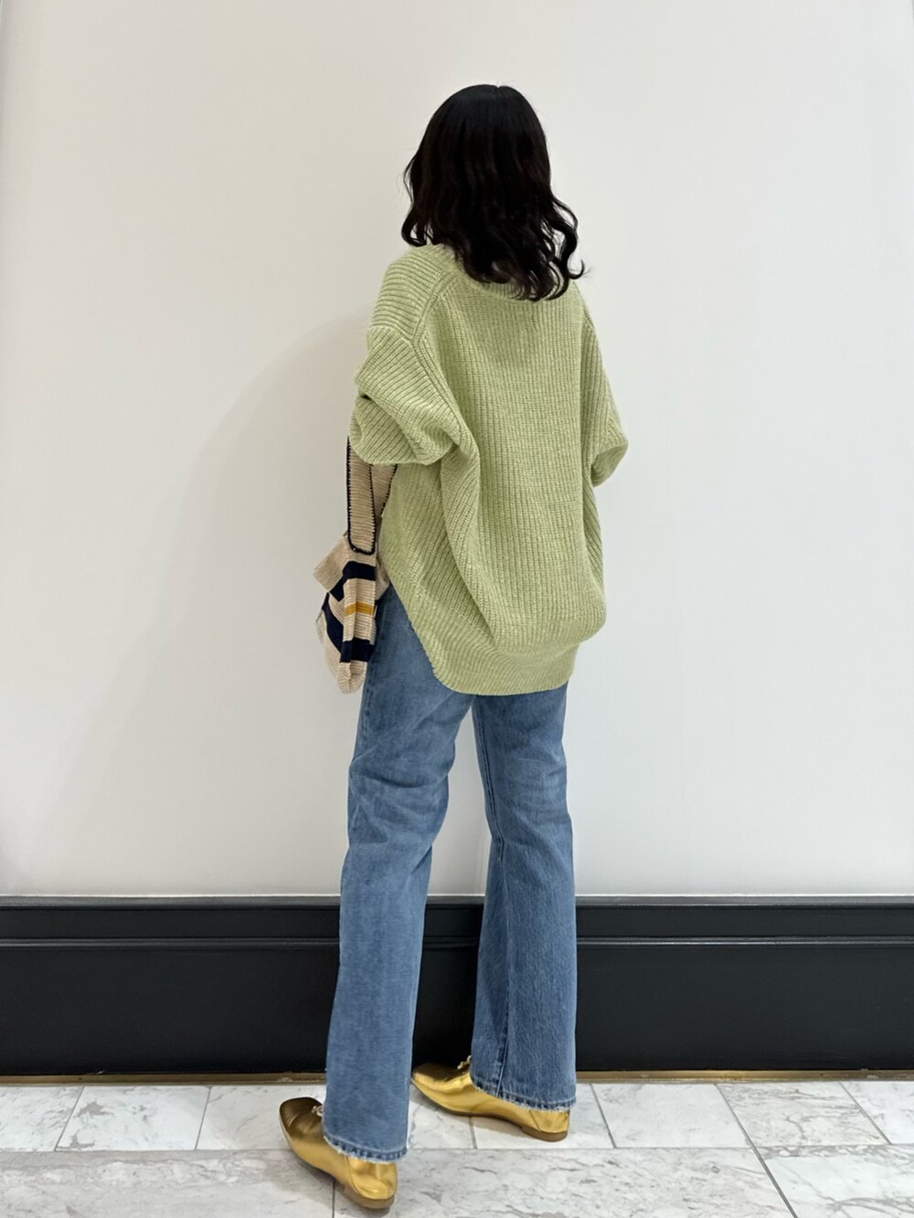 グリーン系のカーディガン/ボレロ、ホワイト系のハンドバッグ、ブルー系のデニムパンツを着用したレディースの冬コーディネートの3枚目の写真