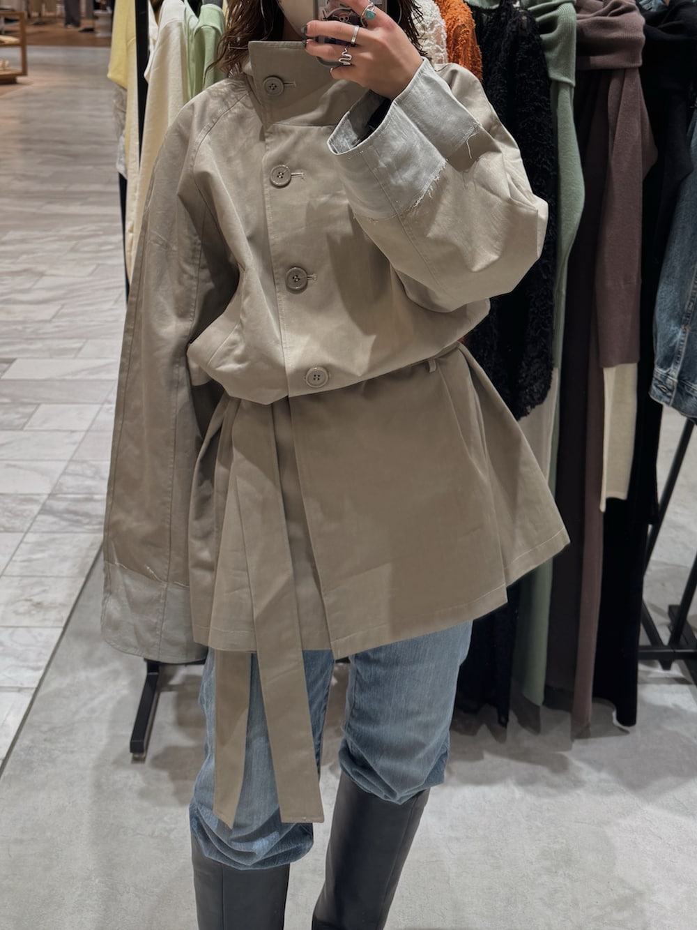 グリーン系のトレンチコート、ブルー系のデニムパンツ、ブラック系のブーツを着用したレディースの冬コーディネートの7枚目の写真