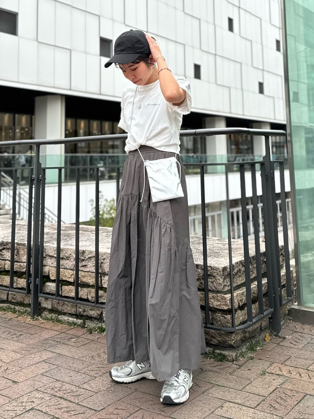 シルバー系のショルダーバッグ、ホワイト系のTシャツ/カットソー、グレー系のスカートを着用したレディースの春コーディネートの2枚目の写真