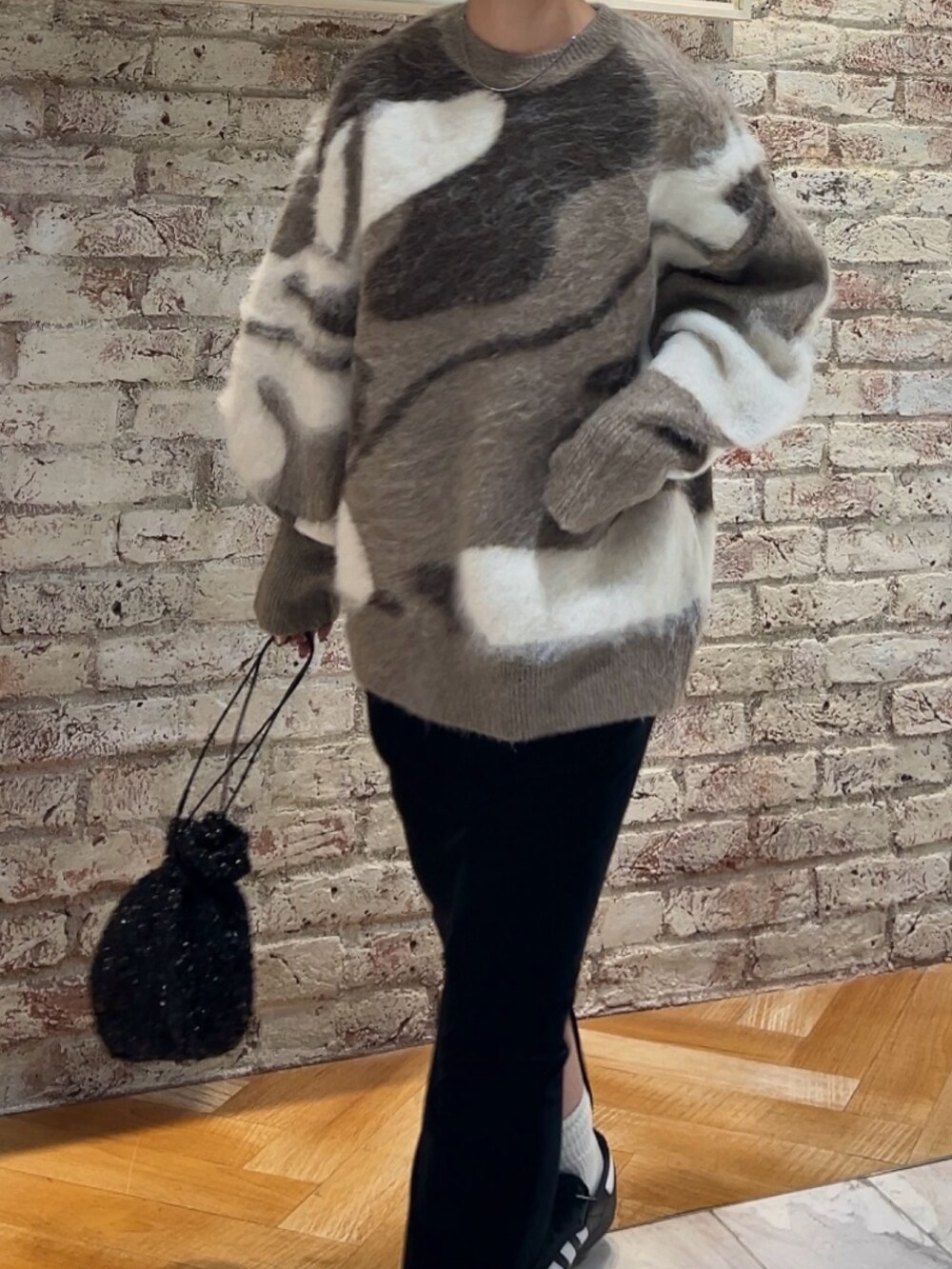 ブラック系のスカート、ブラック系のハンドバッグ、ベージュ系のニット/セーターを着用したレディースの秋コーディネートの2枚目の写真