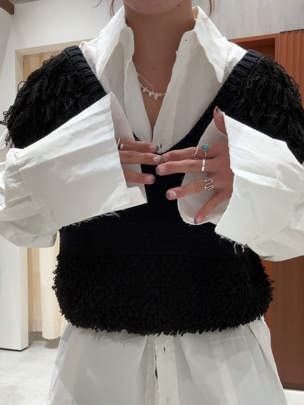 ブラック系のベスト、ホワイト系のシャツ/ブラウス、ブルー系のデニムパンツを着用したレディースの春コーディネートの9枚目の写真