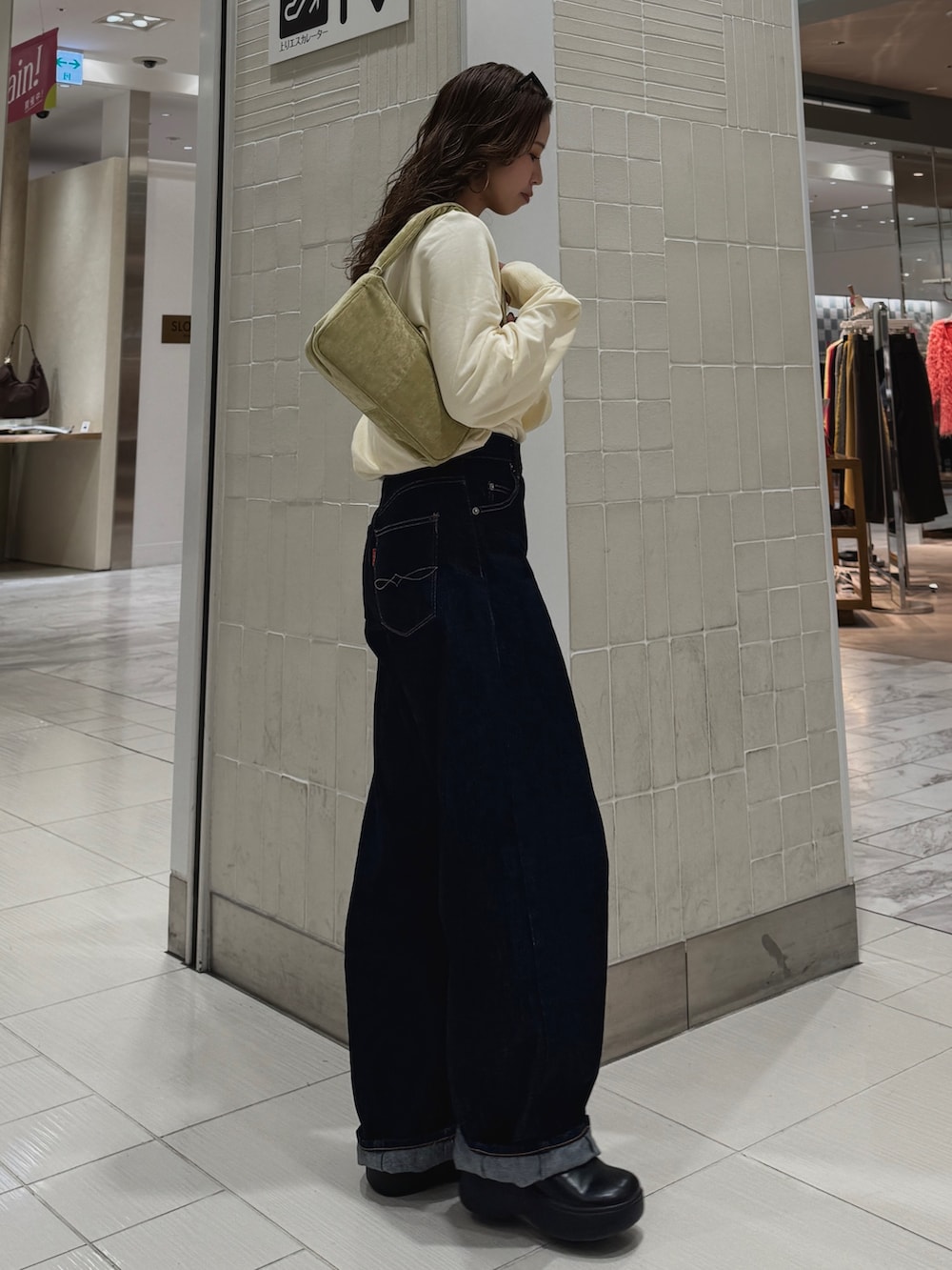 ブルー系のデニムパンツ、ホワイト系のTシャツ/カットソー、グリーン系のハンドバッグを着用したレディースの冬コーディネートの4枚目の写真