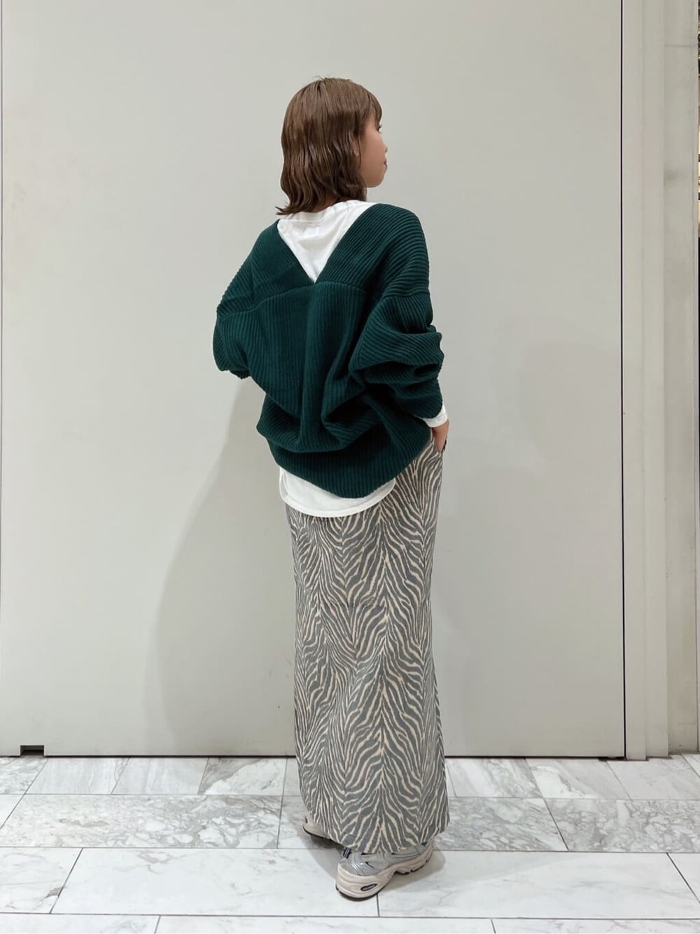 ホワイト系のTシャツ/カットソー、ブルー系のスカート、グリーン系のニット/セーターを着用したレディースの秋コーディネートの6枚目の写真