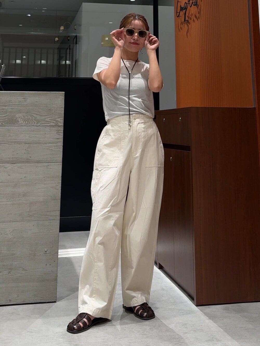 ホワイト系のその他パンツ、ブラウン系のサンダル、ホワイト系のTシャツ/カットソーを着用したレディースの春コーディネートの6枚目の写真
