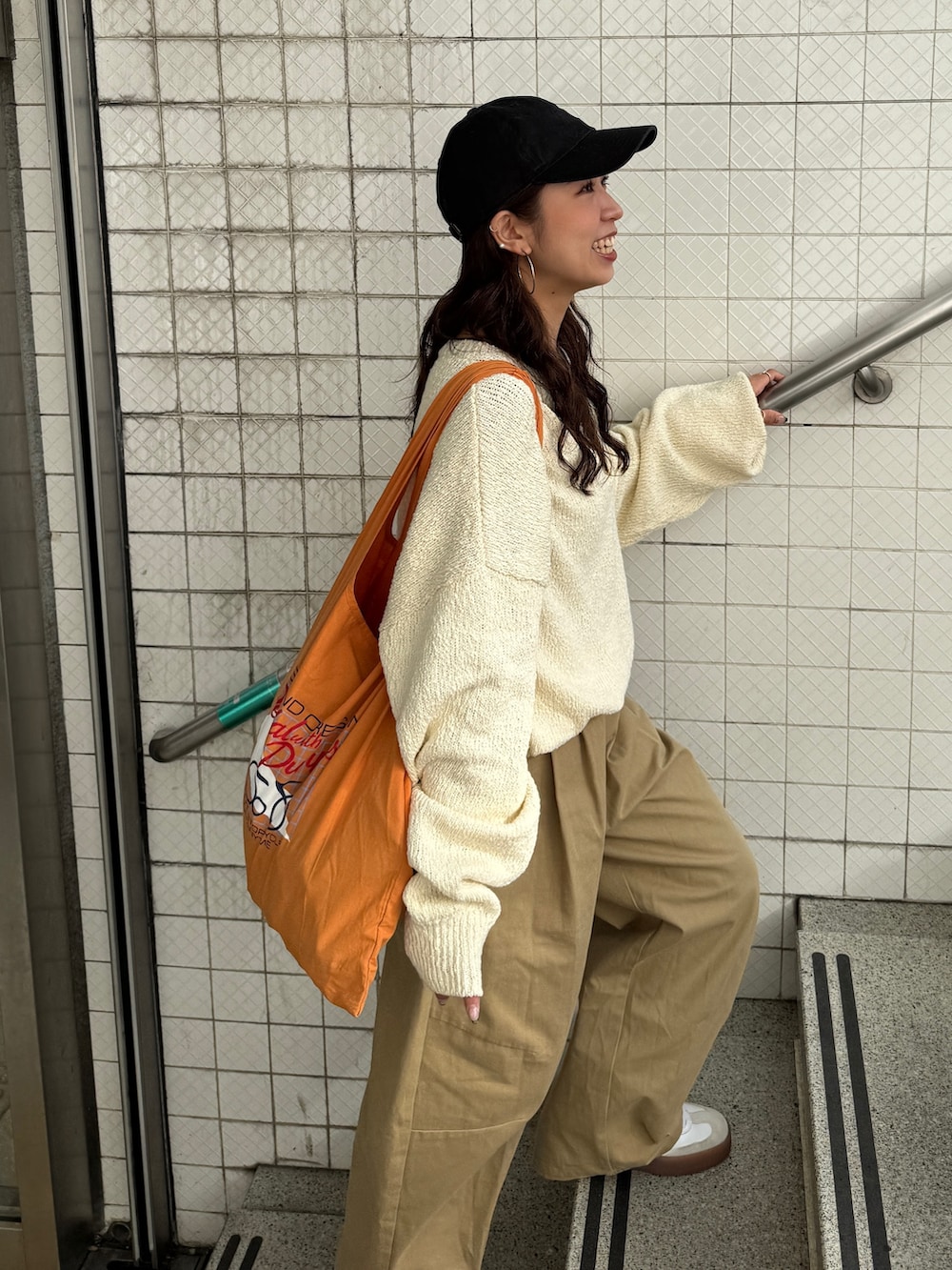 ベージュ系のチノパンツ、ホワイト系のニット/セーター、オレンジ系のエコバッグ/サブバッグを着用したレディースの冬コーディネートの6枚目の写真