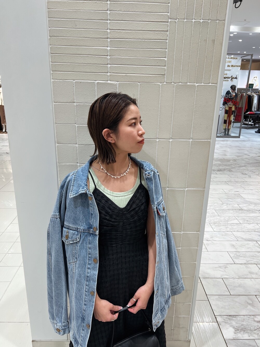 ブラック系のワンピース、グリーン系のタンクトップ、ブルー系のデニムジャケットを着用したレディースの冬コーディネートの8枚目の写真