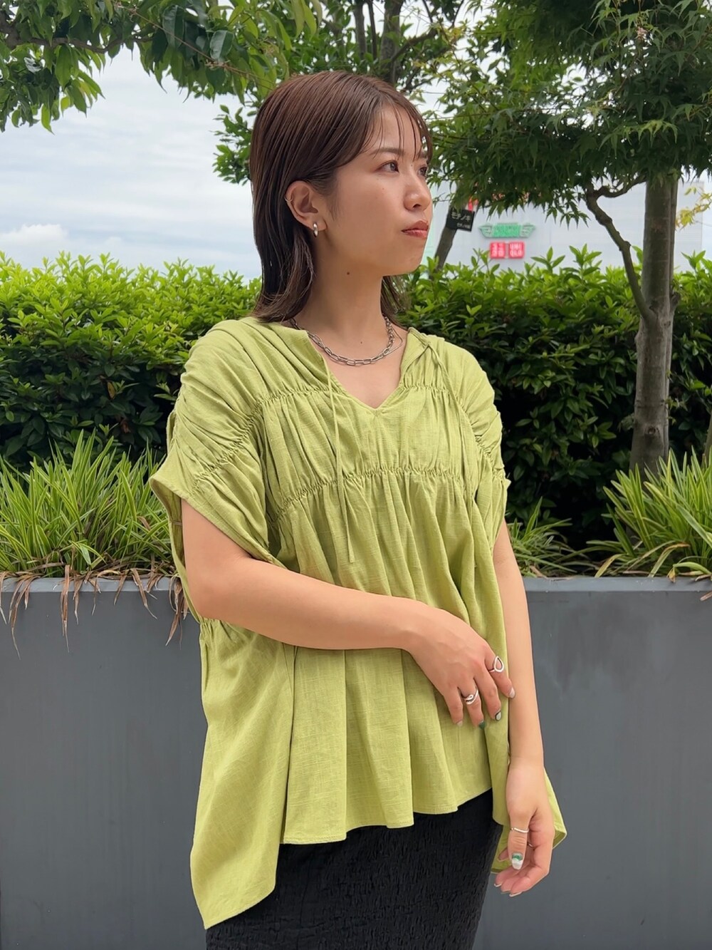 グリーン系のシャツ/ブラウス、ブラック系のスカート、ブラック系のサンダルを着用したレディースの夏コーディネートの4枚目の写真