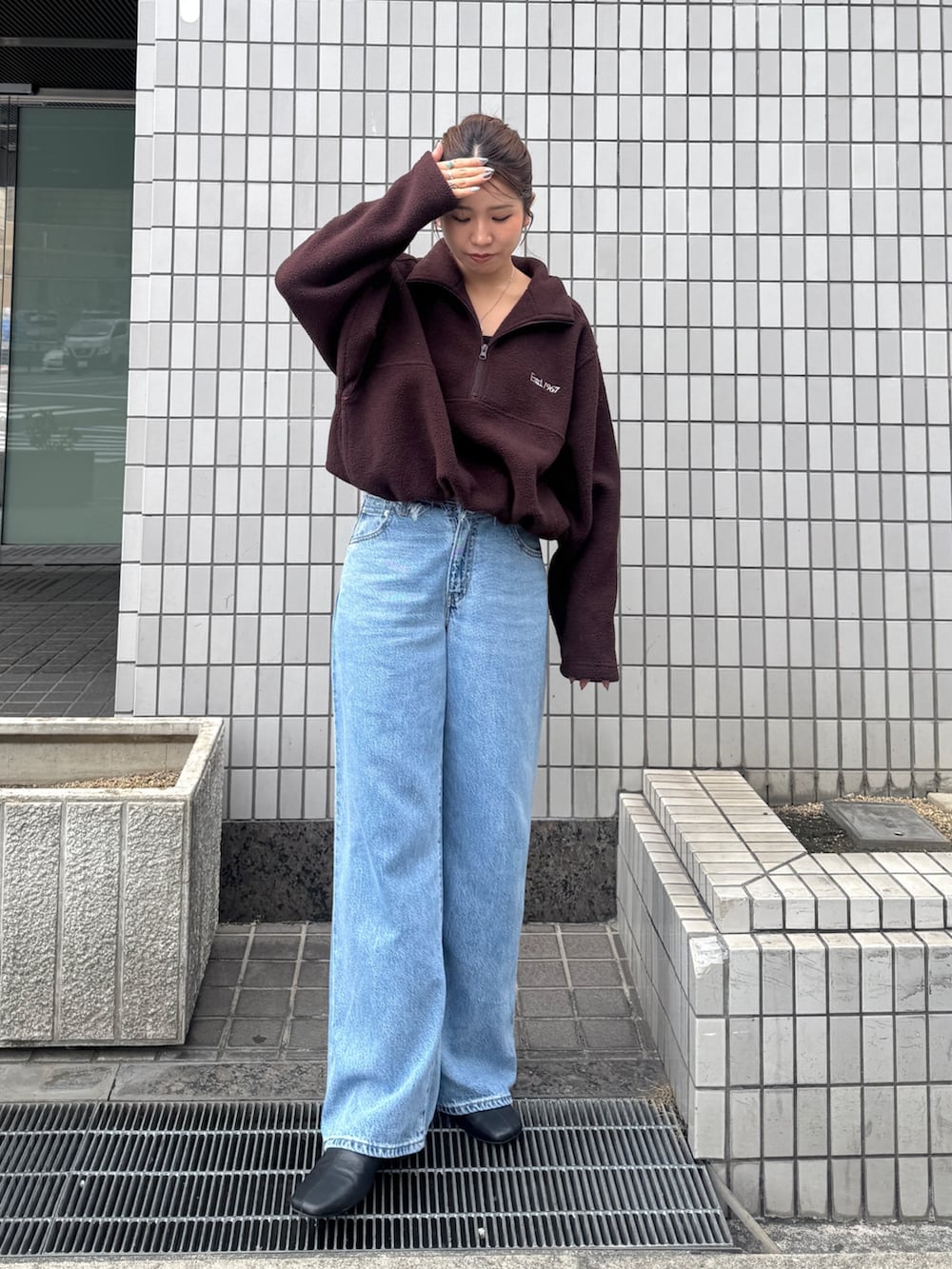 ブラウン系のパーカー、ブルー系のデニムパンツ、ブラック系のサンダルを着用したレディースの秋コーディネートの5枚目の写真