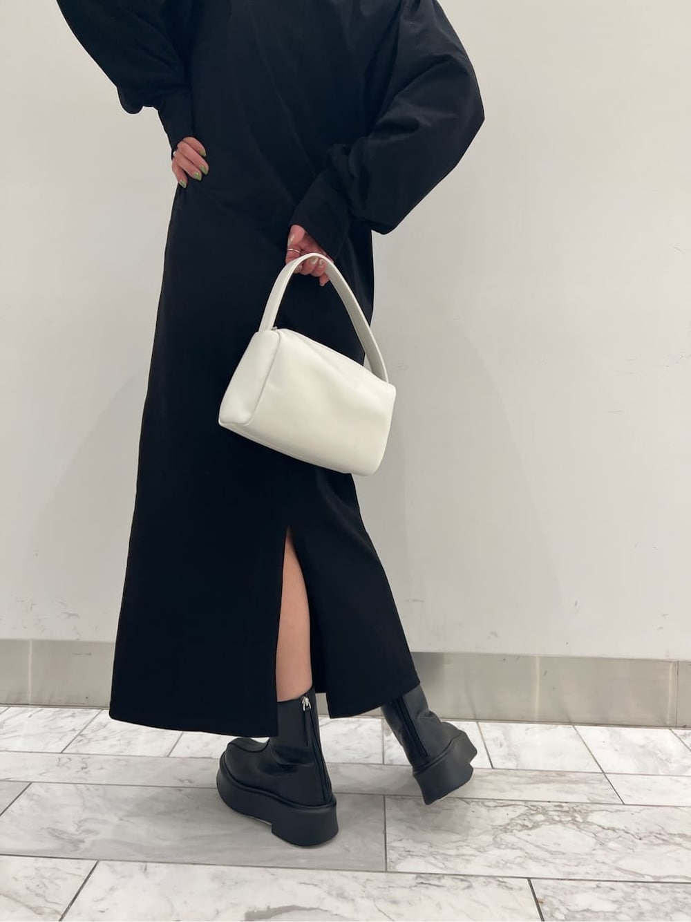 ブラック系のワンピース、ブラック系のブーツ、ホワイト系のハンドバッグを着用したレディースの冬コーディネートの5枚目の写真