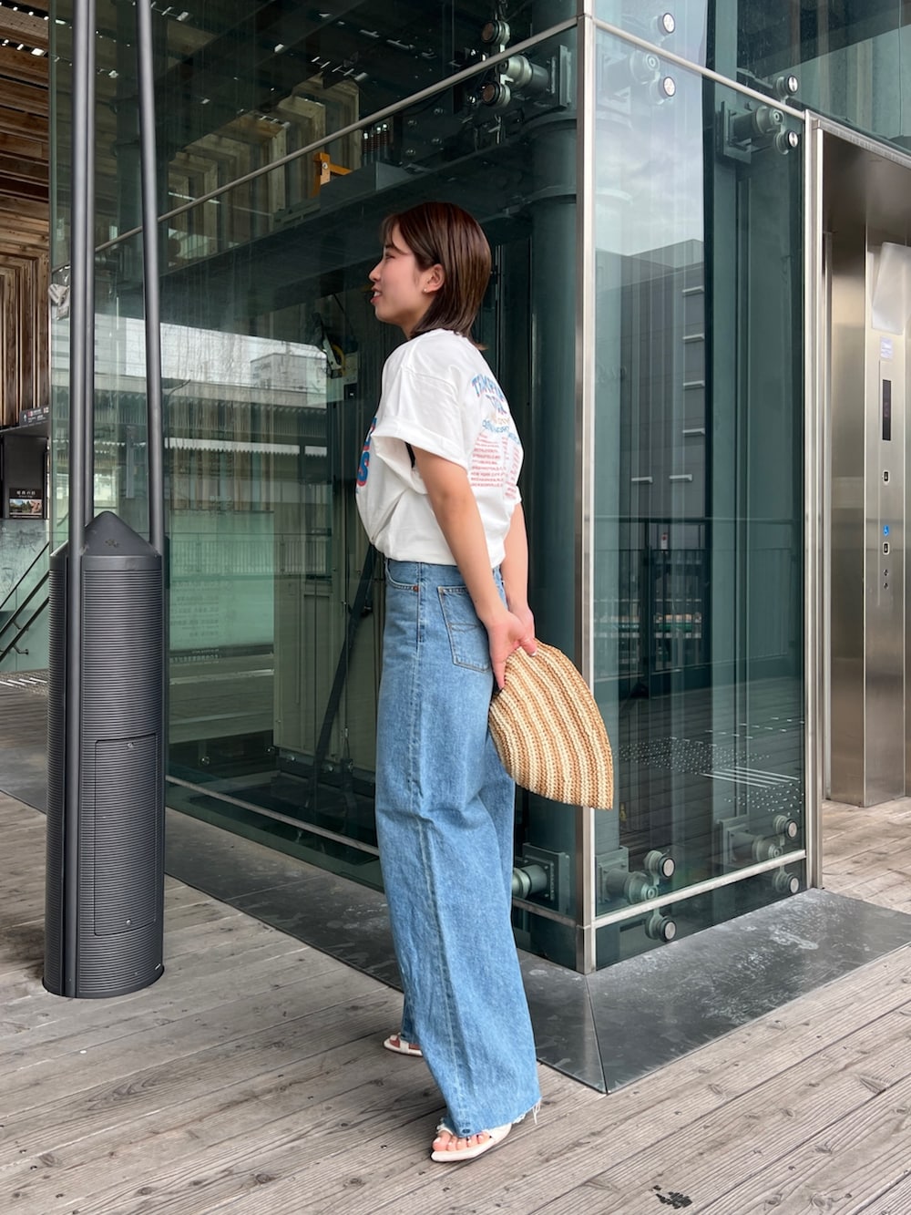 ホワイト系のTシャツ/カットソー、ホワイト系のサンダル、ブルー系のデニムパンツを着用したレディースの春コーディネートの3枚目の写真