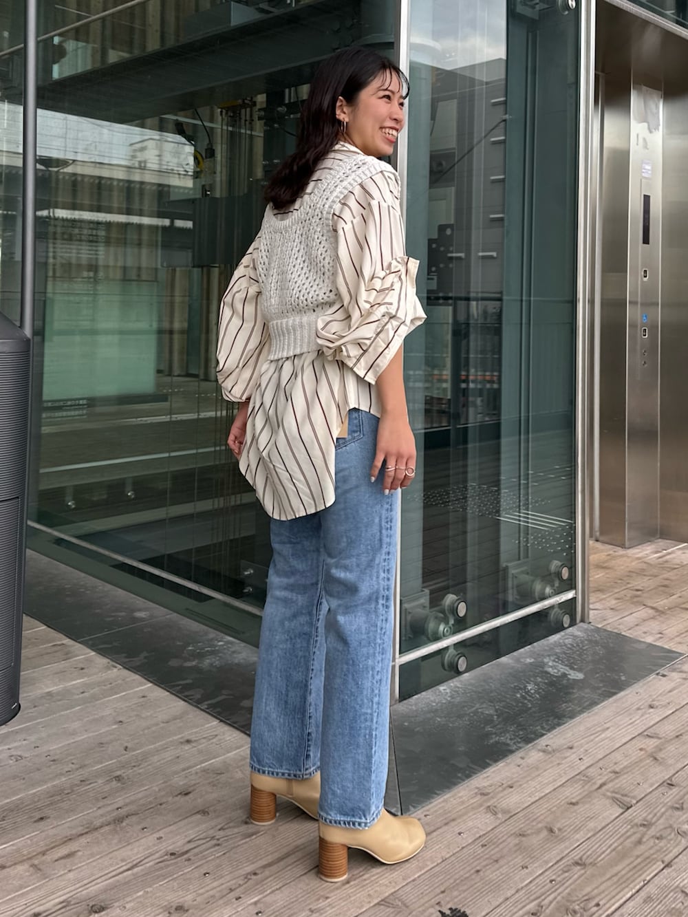 ベージュ系のブーツ、ブルー系のデニムパンツ、イエロー系のシャツ/ブラウスを着用したレディースの冬コーディネートの2枚目の写真