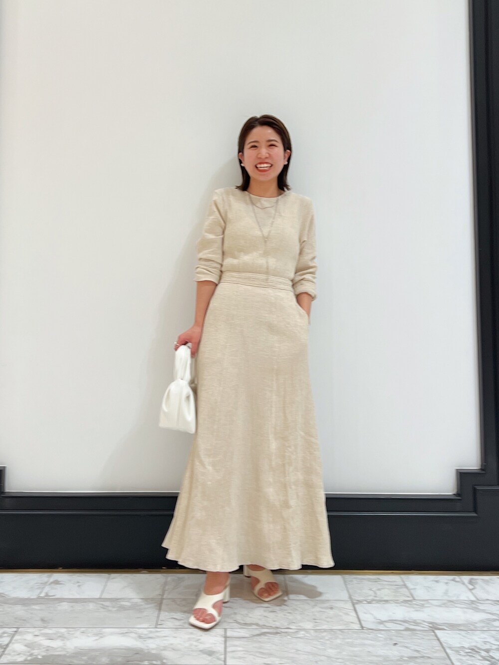 ホワイト系のベスト、ホワイト系のワンピース、ホワイト系のハンドバッグを着用したレディースの春コーディネートの7枚目の写真