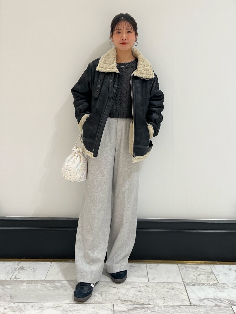 ホワイト系のハンドバッグ、グレー系のニット/セーター、ブラック系のムートンコートを着用したレディースの冬コーディネートの6枚目の写真