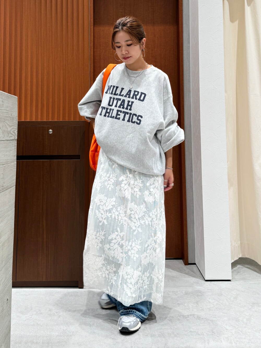 ホワイト系のワンピース、グレー系のスウェット、ブルー系のデニムパンツを着用したレディースの秋コーディネートの9枚目の写真