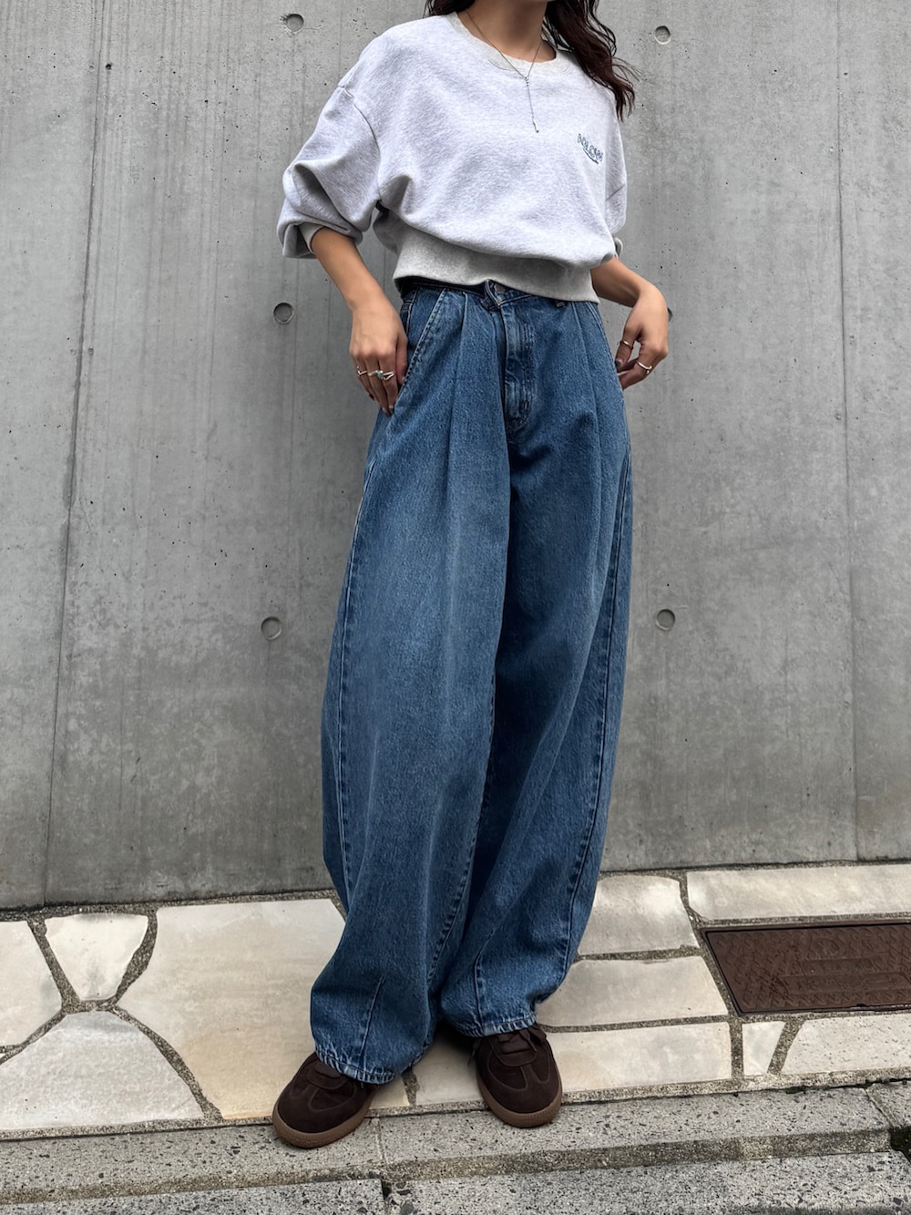 ブルー系のデニムパンツ、グレー系のスウェット、ブラウン系のスニーカーを着用したレディースの秋コーディネートの2枚目の写真