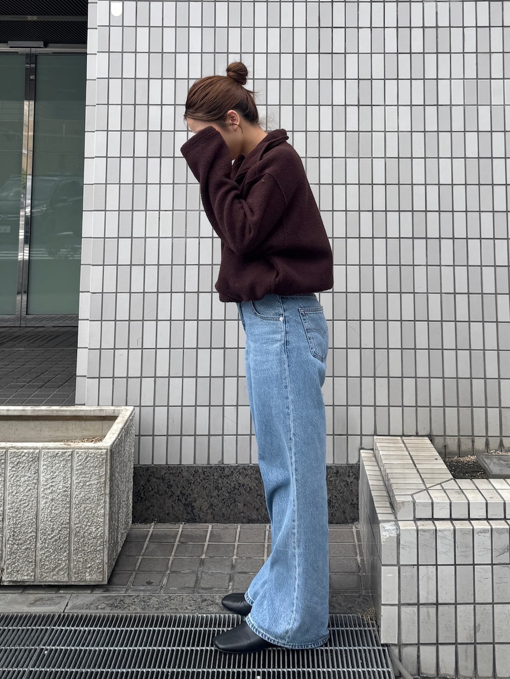 ブラウン系のパーカー、ブルー系のデニムパンツ、ブラック系のサンダルを着用したレディースの秋コーディネートの4枚目の写真