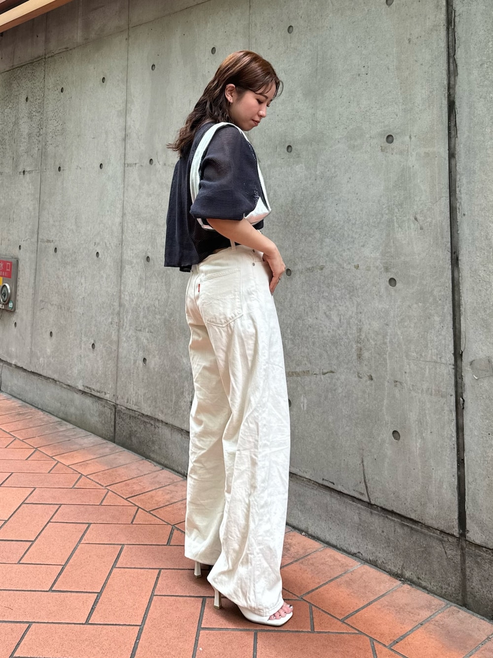 シルバー系のハンドバッグ、ホワイト系のデニムパンツ、グレー系のTシャツ/カットソーを着用したレディースの夏コーディネートの2枚目の写真