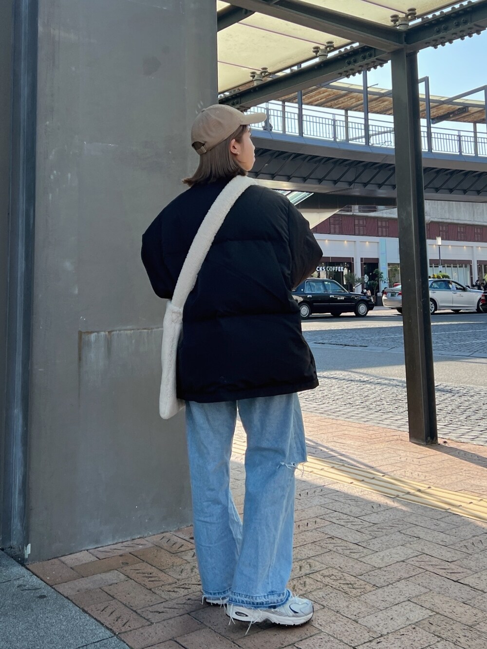 ブラック系のダウンジャケット/コート、ホワイト系のショルダーバッグ、ブルー系のデニムパンツを着用したレディースの秋コーディネートの5枚目の写真