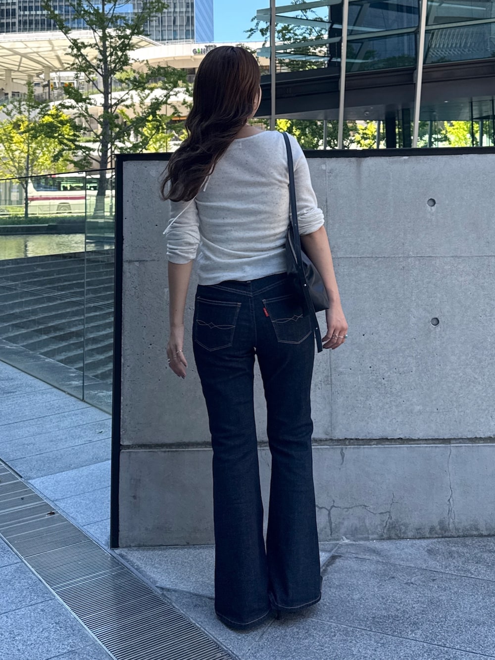 ホワイト系のニット/セーター、ブルー系のデニムパンツ、ブラック系のパンプスを着用したレディースの秋コーディネートの4枚目の写真