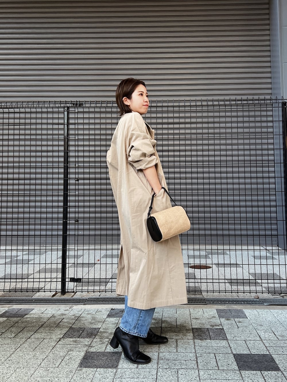 ブルー系のデニムパンツ、ベージュ系のステンカラーコート、グレー系のニット/セーターを着用したレディースの冬コーディネートの3枚目の写真