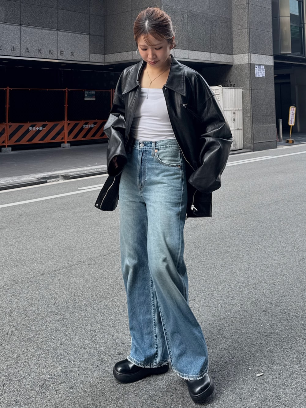 ブラック系のブルゾン、ブルー系のデニムパンツを着用したレディースの秋コーディネートの3枚目の写真
