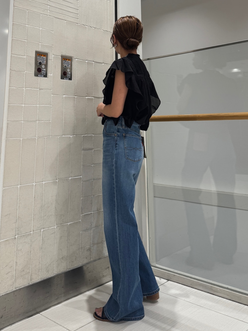 ブルー系のデニムパンツ、ブラック系のシャツ/ブラウス、ブラック系のハンドバッグを着用したレディースの春コーディネートの4枚目の写真
