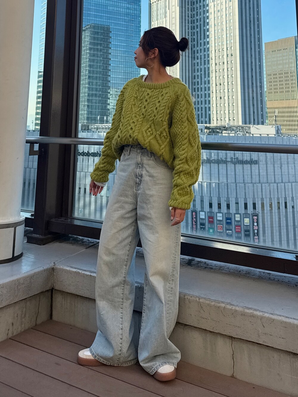 グリーン系のニット/セーター、ホワイト系のTシャツ/カットソー、ブルー系のデニムパンツを着用したレディースの冬コーディネートの2枚目の写真