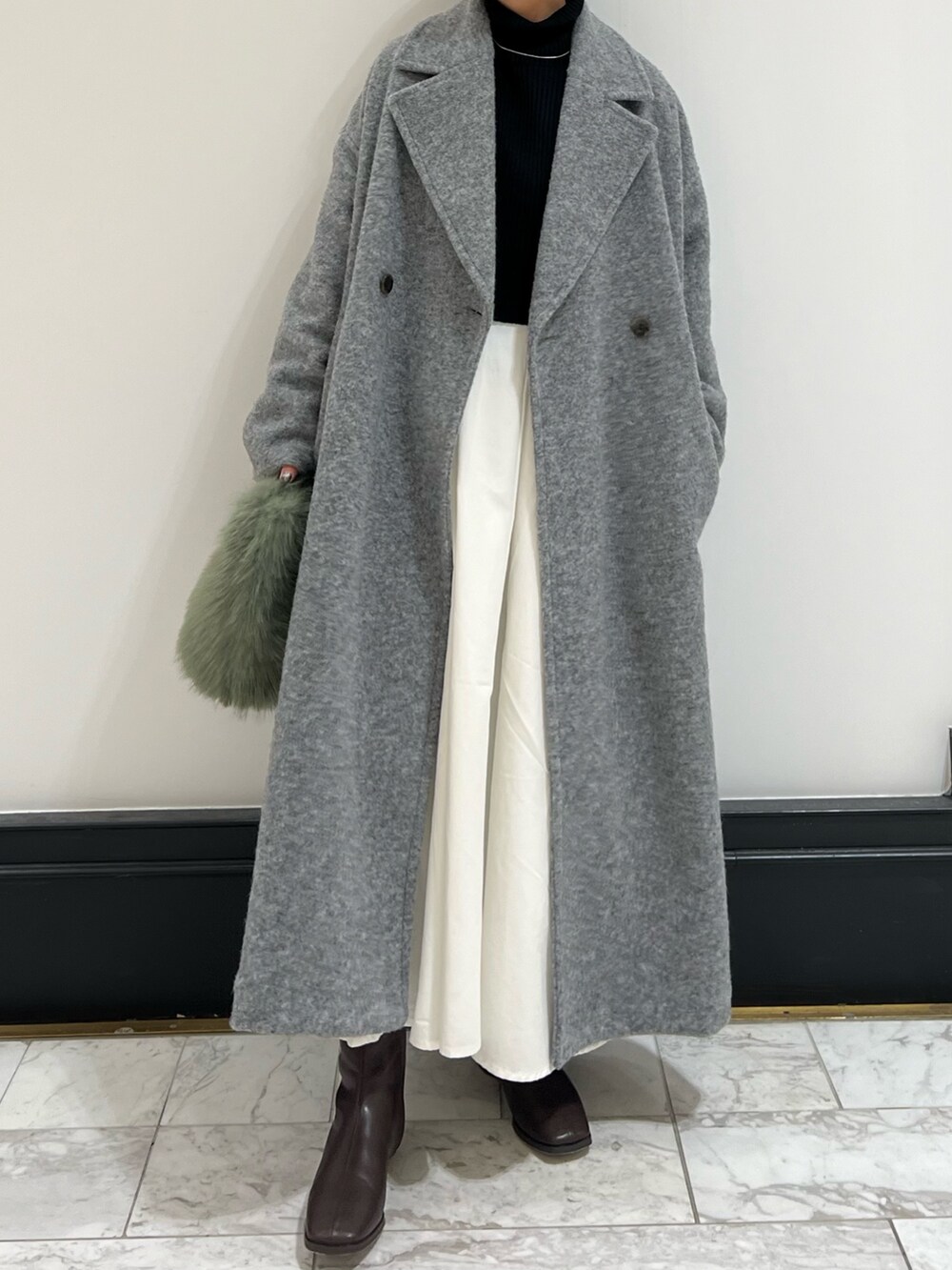 ブラウン系のブーツ、ブラック系のワンピース、グレー系のチェスターコートを着用したレディースの冬コーディネートの7枚目の写真