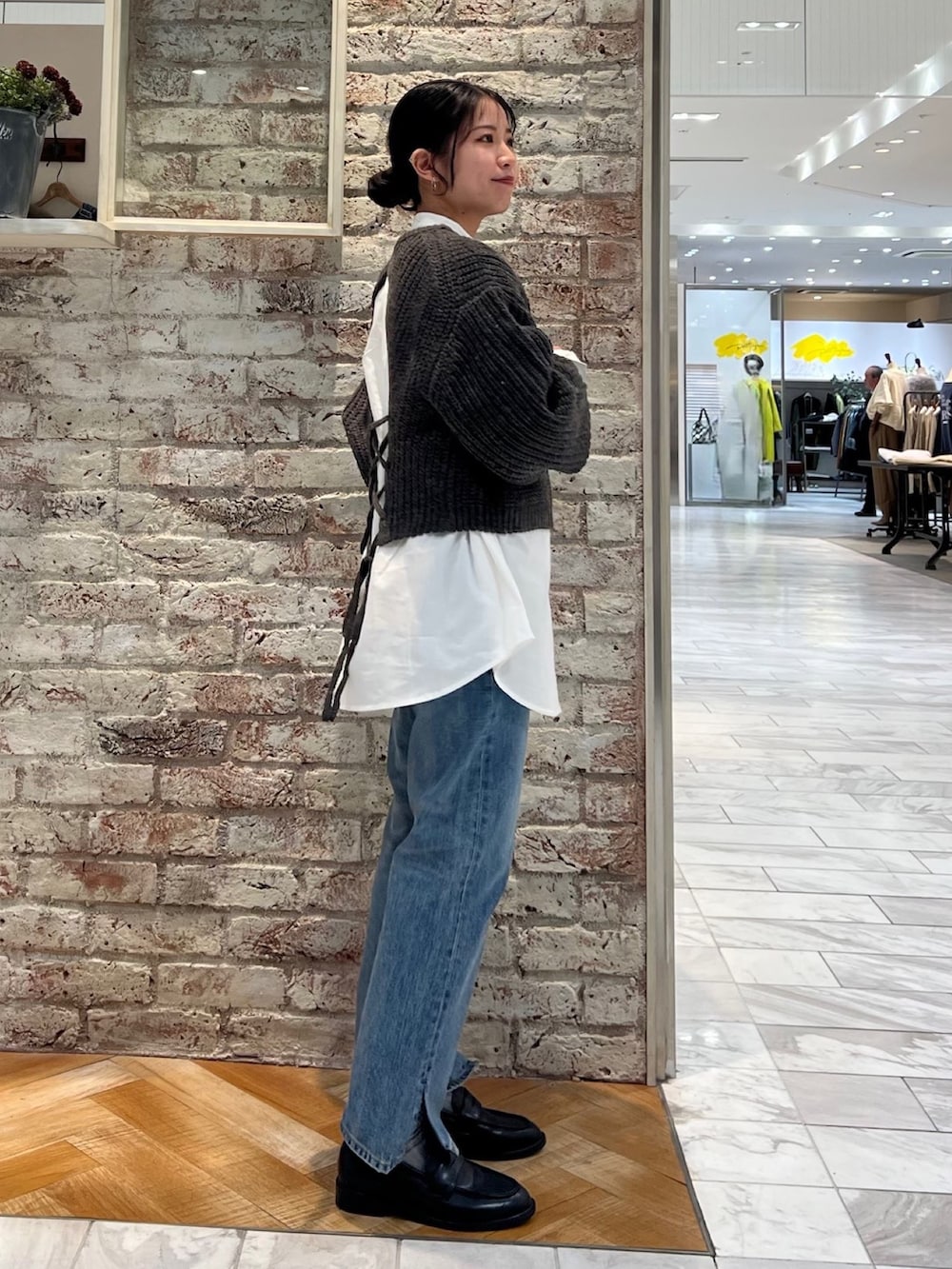 グレー系のニット/セーター、ブルー系のデニムパンツ、ブラック系のローファーを着用したレディースの秋コーディネートの6枚目の写真