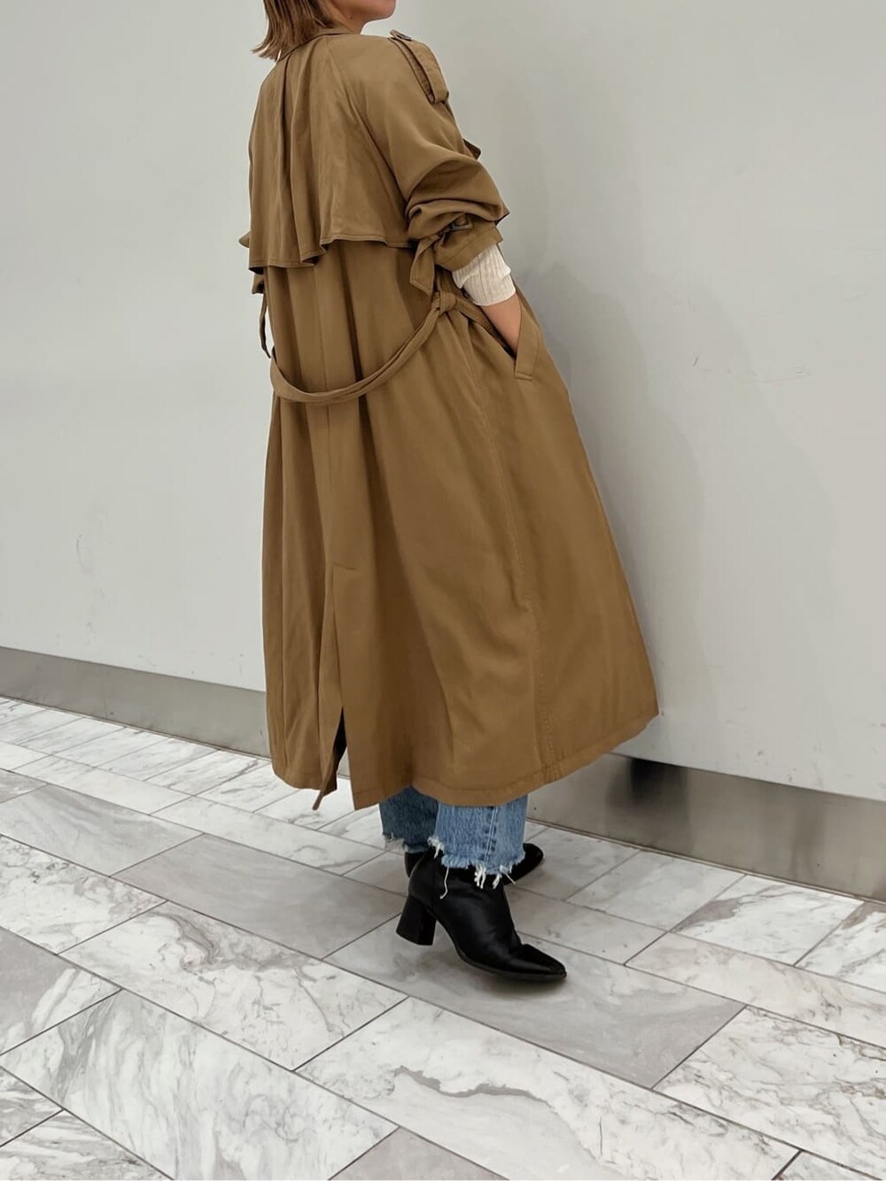 ブラウン系のトレンチコート、ブラック系のブーツ、ホワイト系のニット/セーターを着用したレディースの夏コーディネートの2枚目の写真