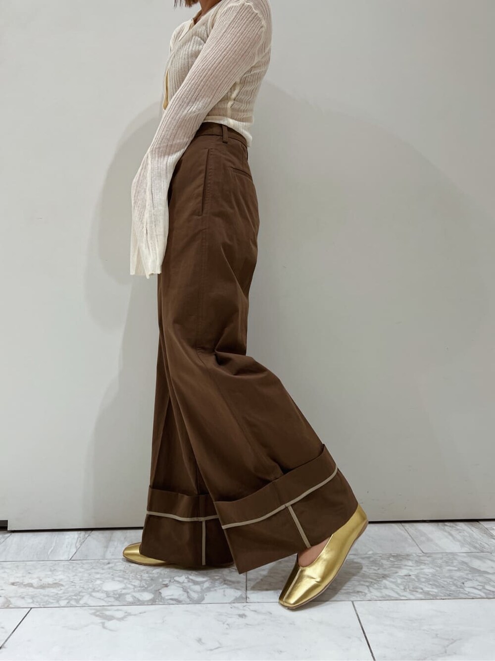 ブラウン系のチノパンツ、ゴールド系のパンプス、ホワイト系のカーディガン/ボレロを着用したレディースの夏コーディネートの6枚目の写真