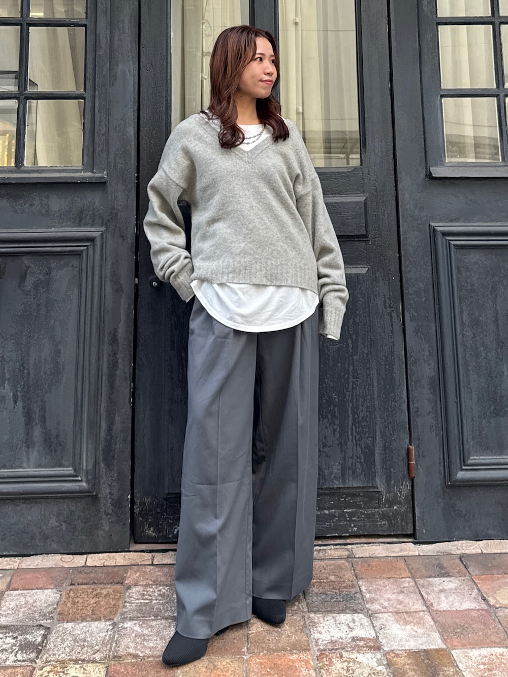 グレー系のニット/セーター、ホワイト系のTシャツ/カットソー、グレー系のその他パンツを着用したレディースの冬コーディネートの6枚目の写真