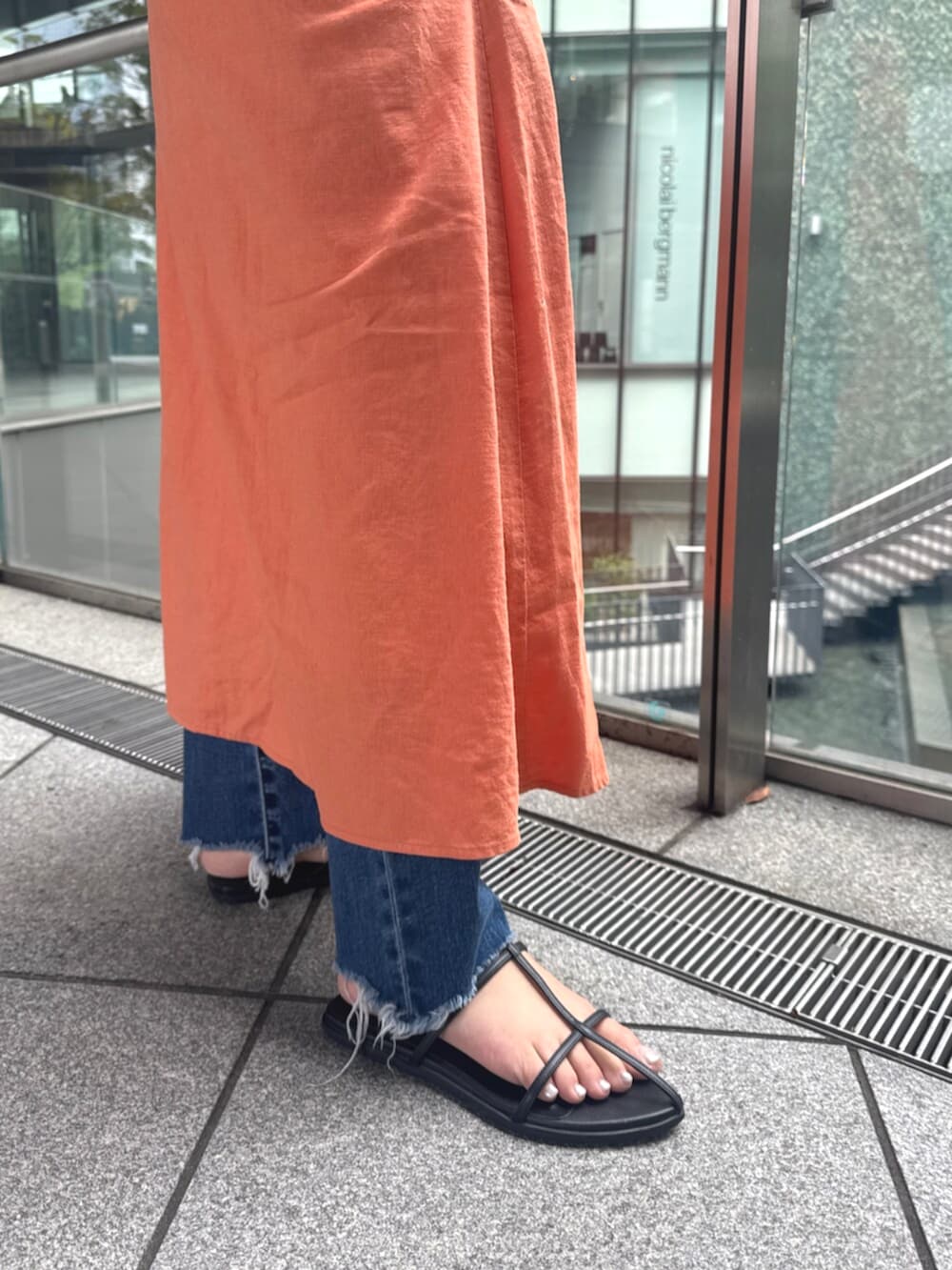 ブルー系のデニムパンツ、オレンジ系のワンピースを着用したレディースの春コーディネートの9枚目の写真