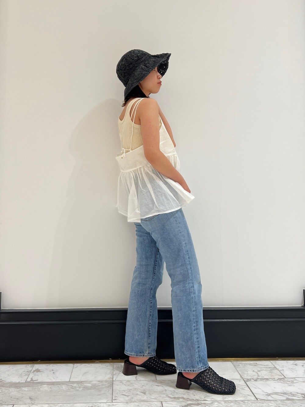 ホワイト系のシャツ/ブラウス、ベージュ系のタンクトップ、ブルー系のデニムパンツを着用したレディースの春コーディネートの2枚目の写真