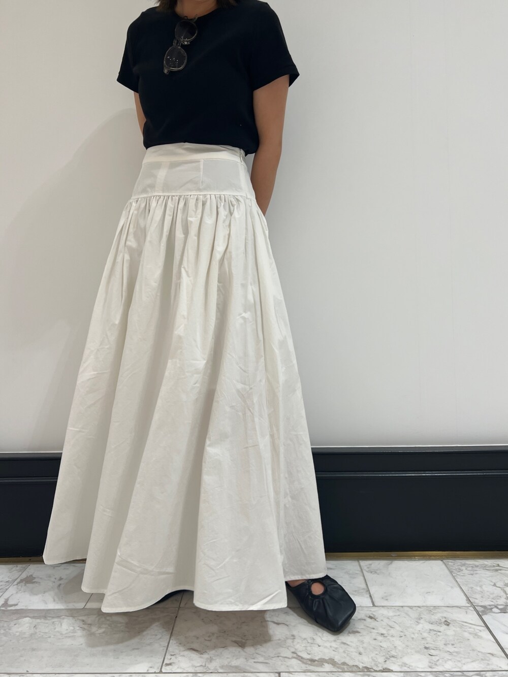 ホワイト系のスカート、ブラック系のTシャツ/カットソー、ブラック系のパンプスを着用したレディースの春コーディネートの6枚目の写真