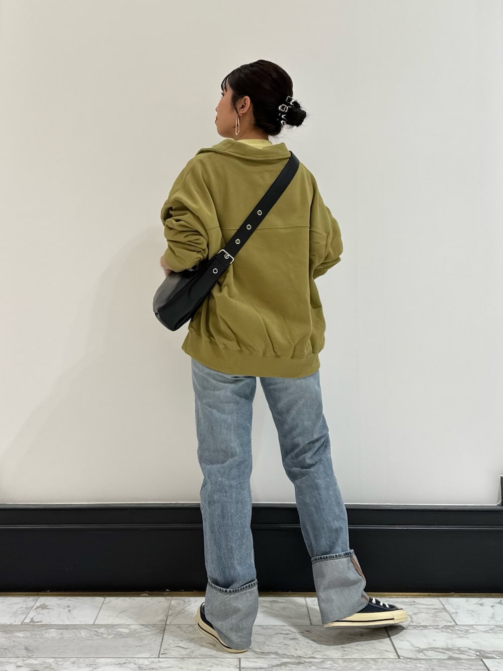 グリーン系のスウェット、ブラック系のショルダーバッグ、イエロー系のTシャツ/カットソーを着用したレディースの冬コーディネートの4枚目の写真