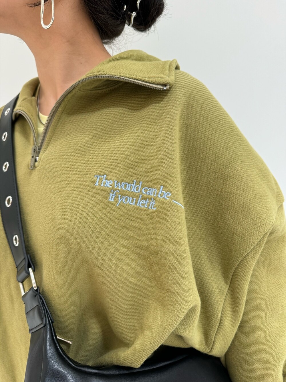 グリーン系のスウェット、ブラック系のショルダーバッグ、イエロー系のTシャツ/カットソーを着用したレディースの冬コーディネートの6枚目の写真